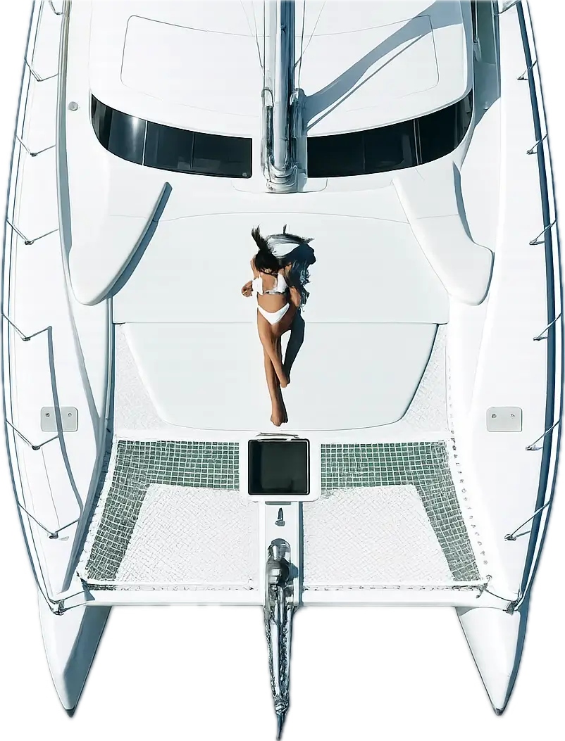 A woman in a white bikini lying on the deck of a white catamaran yacht from an aerial view.
